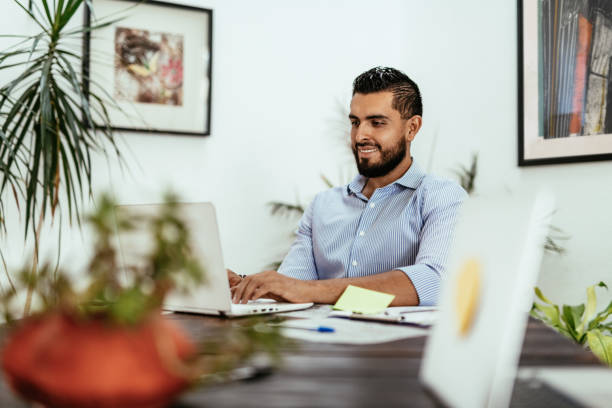 istock Latin businessman working on laptop and smiling 1167911502