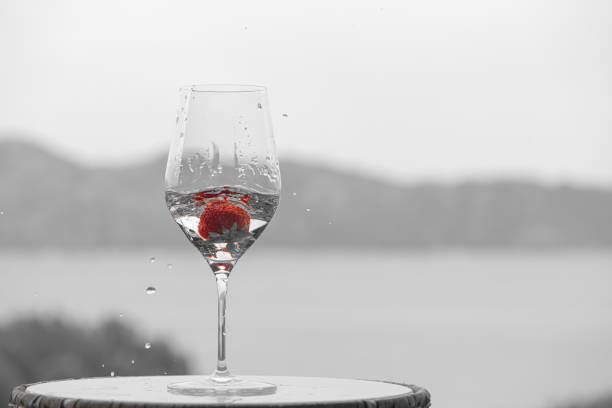 Selective color of  a red strawberry falling in a black and white crystal glass