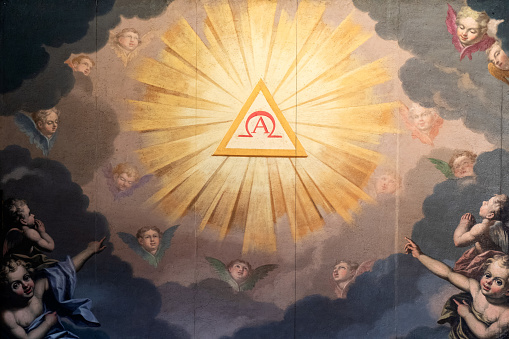 Rome, Italy - August 13, 2019: Church of the Gesù, Angels' chapel having the painting by Federico Zuccaro (1542-1609). That artwork shows the angels worshipping the Holy Trinity represented by the triangle and the letters Alpha and Omega. Detail of the Holy Trinity.