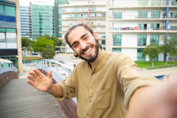 istock Joyful happy hipster guy waving hello at phone camera 1167918469