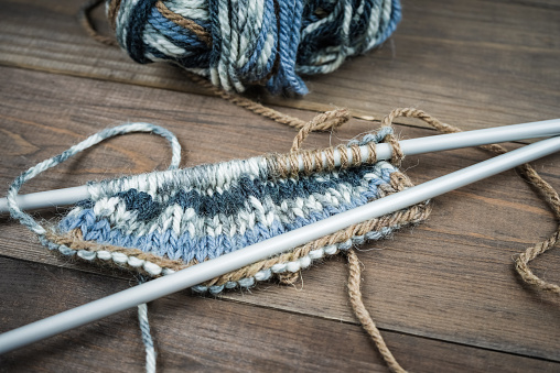 Color thread for knitting, knitted scarf, knitting needles on a dark wooden background. Copy space. Knitting concept