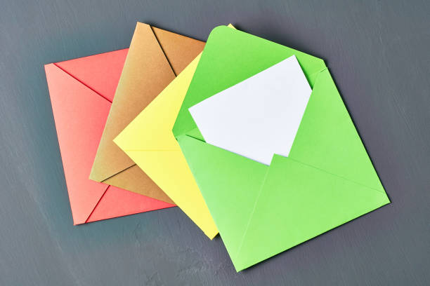istock Blank white paper sheet in green opened square envelope lies on old scratched dark concrete. Space for text. Top view 1167920211