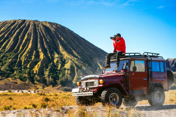 reisende sitzen und machen ein foto auf einem oldtimer off-road-auto - bromo crater stock-fotos und bilder