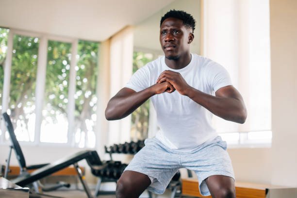 desportista do americano africano que cócoras na ginástica - men exercising equipment relaxation exercise - fotografias e filmes do acervo