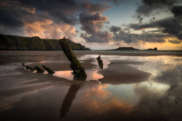 The Helvetia after the rain Rhossili Bay and Worms Head showing remains of the ship The Helvetia, a Norwegian barque, which was wrecked during a storm in 1887 on the Gower peninsula, South Wales, UK rhossili bay stock pictures, royalty-free photos & images