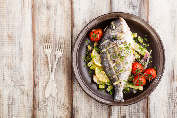istock Baked whole fish, served with roasted vegetables and lemon. 1167931762
