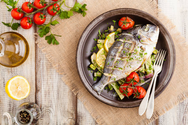 istock Baked whole fish, served with roasted vegetables and lemon. 1167931772