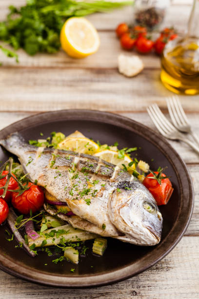 istock Baked whole fish, served with roasted vegetables and lemon. 1167931783