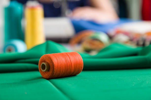 Sewing workshop. Sewing clothes. Closeup on a spool of thread. Photographic concept.