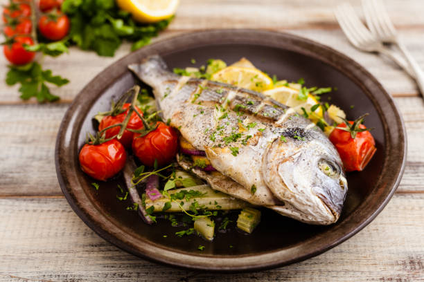 istock Baked whole fish, served with roasted vegetables and lemon. 1167933596