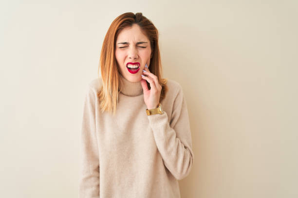 istock Redhead woman wearing elegant turtleneck sweater standing over isolated white background touching mouth with hand with painful expression because of toothache or dental illness on teeth. Dentist concept. 1167933603