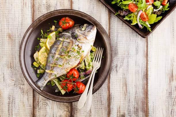 istock Baked whole fish, served with roasted vegetables and lemon. 1167933647