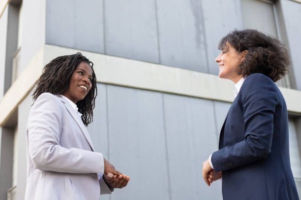 istock Smiling businesswomen talking while standing near building. 1167934073