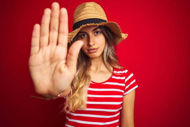 istock Young beautiful woman wearing summer hat over red isolated background with open hand doing stop sign with serious and confident expression, defense gesture 1167936099