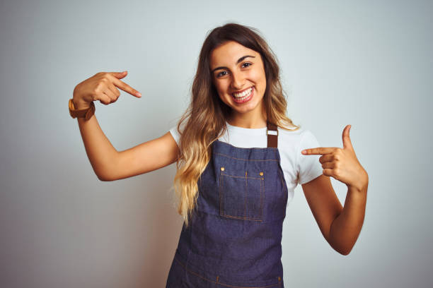 Young beautiful woman wearing apron over grey isolated background looking confident with smile on face, pointing oneself with fingers proud and happy. Young beautiful woman wearing apron over grey isolated background looking confident with smile on face, pointing oneself with fingers proud and happy. first job photos stock pictures, royalty-free photos & images