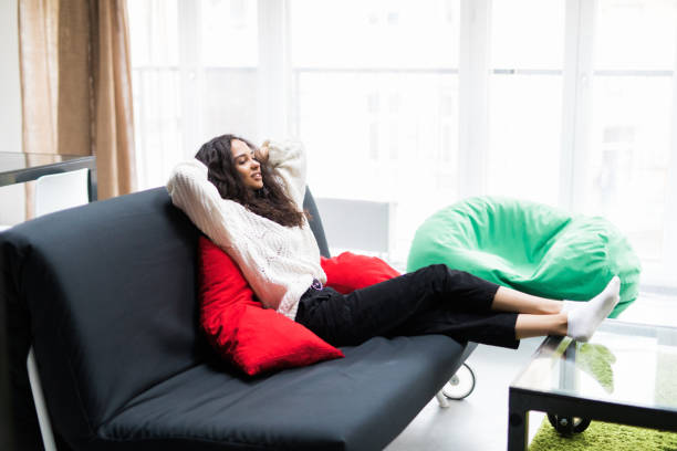 istock Young smiling woman lying relaxed on couch 1167938321