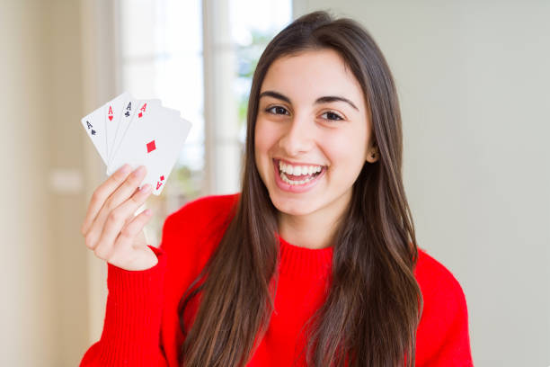 beautiful young woman gambling playing poker with a happy face standing and smiling with a confident smile showing teeth - smiling casino human hand beautiful imagens e fotografias de stock