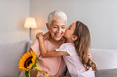 Happy little girl giving bouquet of flowers to her grandmother