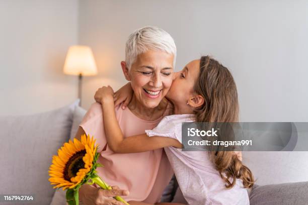 Happy Little Girl Giving Bouquet Of Flowers To Her Grandmother Stock Photo - Download Image Now