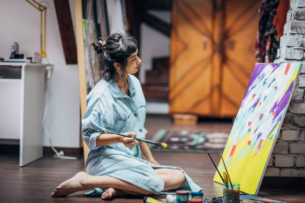 istock Young lady painter painting on the floor at home 1167943023