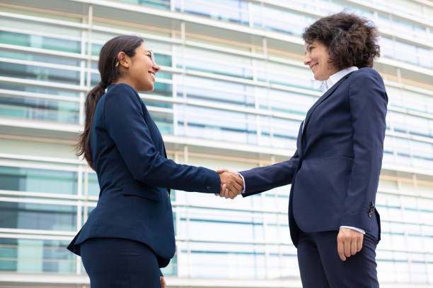 istock Smiling businesswomen shaking hands near office. 1167943237