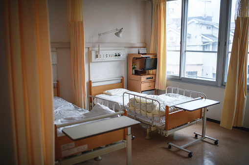General view of Tokyo hospital room with empty beds lit by natural window light.