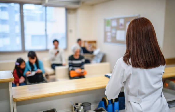 jeune infirmière japonaise femelle faisant face aux patients dans la salle d'attente - japan serious family senior adult photos et images de collection