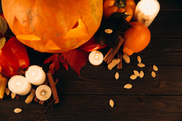 istock Shiny candles, cinnamon and fallen leaves stand before scarry Halloween pumpkin 1167945381