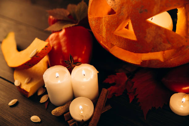 istock Shiny candles, cinnamon and fallen leaves stand before scarry Halloween pumpkin 1167946089