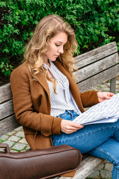 istock Girl studies music notes sitting on bench in park 1167947411