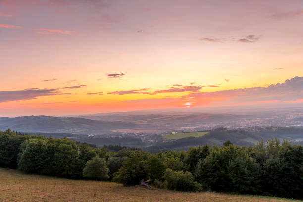 istock Sunset with view on landscape with fully colored clouds orange and purple and sun behind it and city Valasske Mezirici captured during summer late time. 1167947995