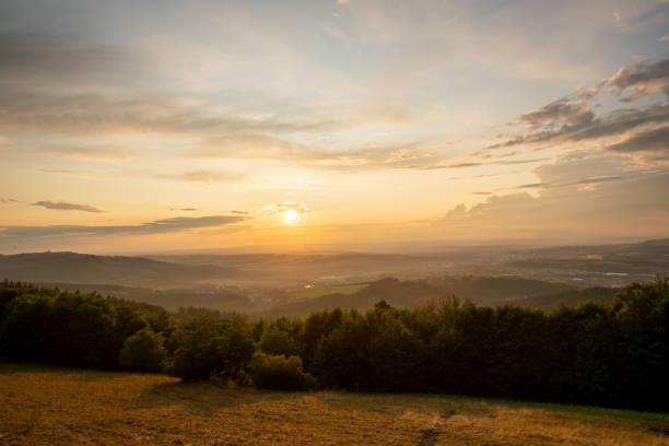 istock Sunset with view on landscape with fully colored clouds orange and purple and sun behind it and city Valasske Mezirici captured during summer late time. 1167947997