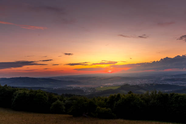 istock Sunset with view on landscape with fully colored clouds orange and purple and sun behind it and city Valasske Mezirici captured during summer late time. 1167948549