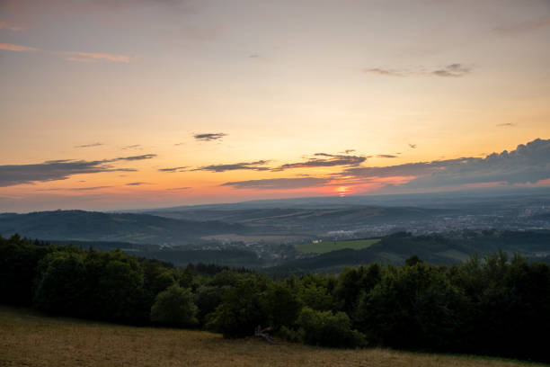 istock Sunset with view on landscape with fully colored clouds orange and purple and sun behind it and city Valasske Mezirici captured during summer late time. 1167948551