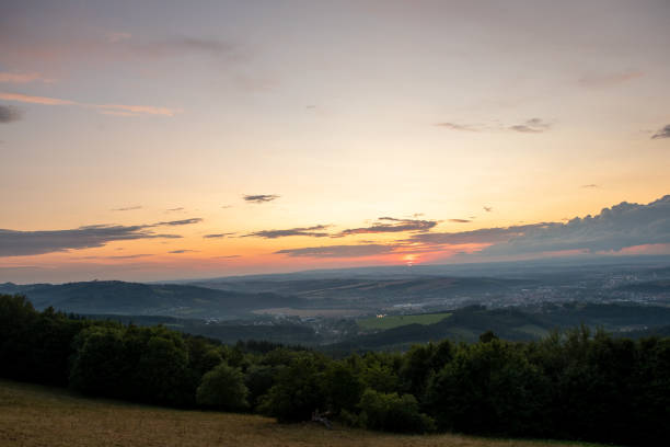 istock Sunset with view on landscape with fully colored clouds orange and purple and sun behind it and city Valasske Mezirici captured during summer late time. 1167949121