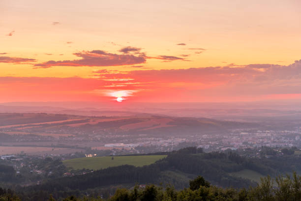 istock Sunset with view on landscape with fully colored clouds and orange sun goes down and city Valasske Mezirici captured during summer late time 1167949319
