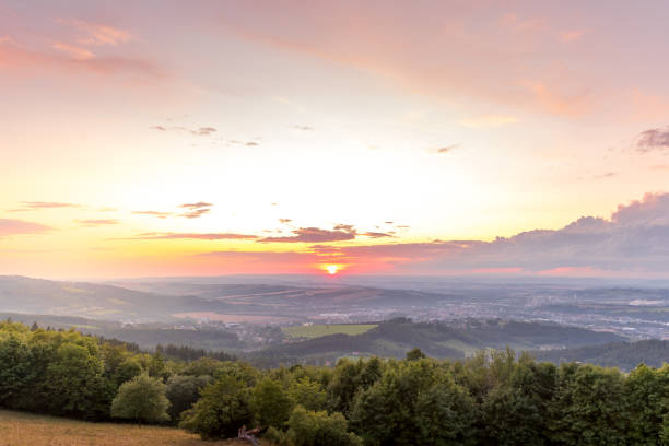 istock Sunset with view on landscape with fully colored clouds and orange sun goes down and city Valasske Mezirici captured during summer late time 1167949557