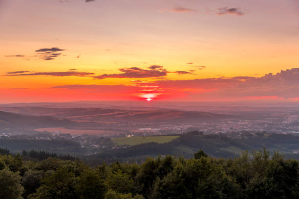 istock Sunset with view on landscape with fully colored clouds and orange sun goes down and city Valasske Mezirici captured during summer late time 1167949846