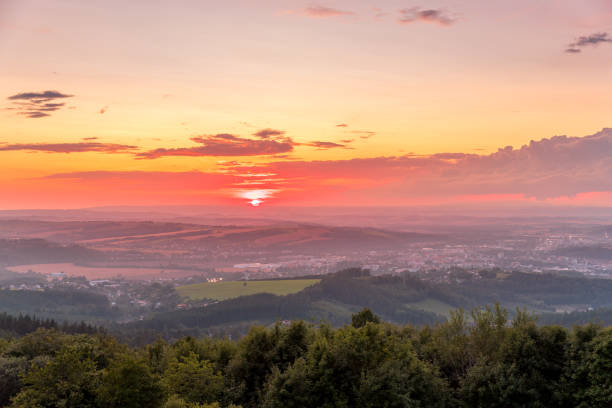 istock Sunset with view on landscape with fully colored clouds and orange sun goes down and city Valasske Mezirici captured during summer late time 1167949854