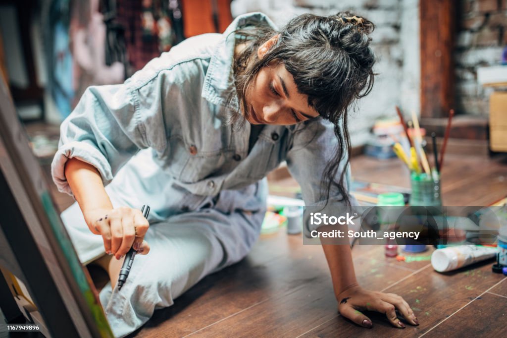Woman painting on the floor at home One woman, beautiful lady artist, painting on the floor in studio. Artist Stock Photo