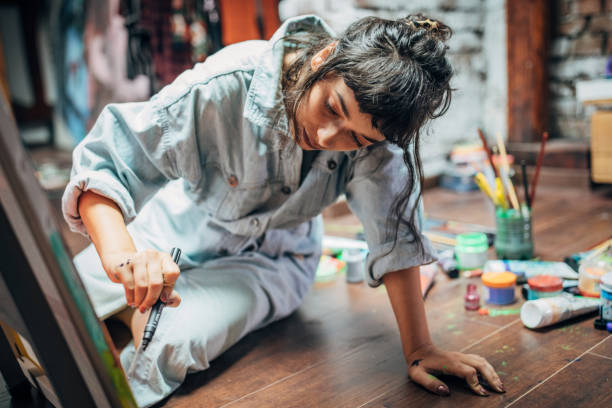 Woman painting on the floor at home One woman, beautiful lady artist, painting on the floor in studio. workshop art studio art paint stock pictures, royalty-free photos & images