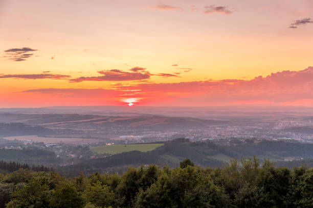 istock Sunset with view on landscape with fully colored clouds and orange sun goes down and city Valasske Mezirici captured during summer late time 1167949911