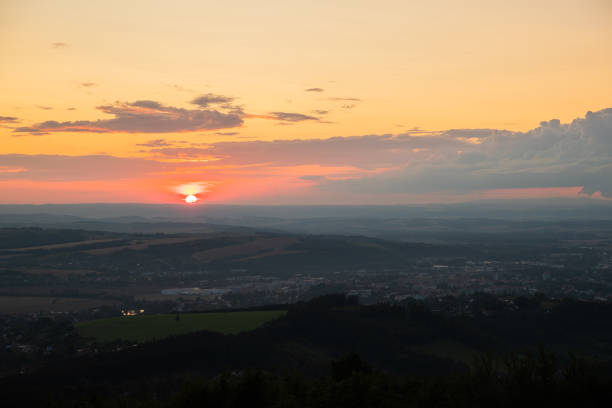 istock Sunset with view on landscape with fully colored clouds and orange sun goes down and city Valasske Mezirici captured during summer late time 1167950201