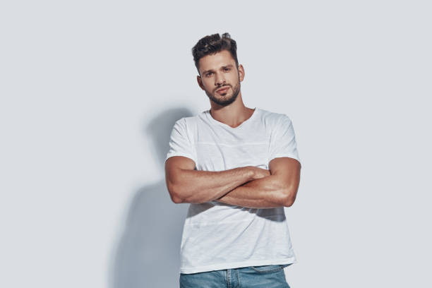 istock Handsome young man looking at camera and keeping arms crossed while standing against grey background 1167953861