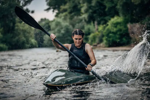 Whitewater kayaking, extreme kayaking. Woman in a kayak sails on a mountain river