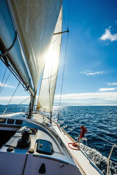 Sailing with sailboat towards the sun on summer sunny day.