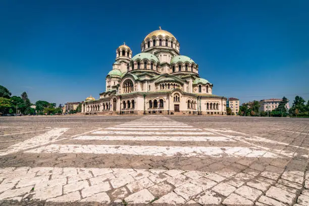 Panoramic wide angle and high detail photograph of Alexander Nevsky Patriarchal Cathedral, downtown district in city of Sofia, capital of Bulgaria, Eastern Europe on a clear sunny day with blue sky and no clouds. Built in Neo-Byzantine style, it serves as the cathedral church of the Patriarch of Bulgaria and it is believed to be one of the top 500 largest Christian church buildings. It is one of Sofia's symbols and primary tourist attractions. The St. Alexander Nevsky Cathedral in Sofia occupies an area of 3,170 square metres (34,100 sq ft) and can hold 5,000 people inside. Shot on Canon EOS R full frame system RF premium lens for best quality. The image has plenty of copy space for your message.