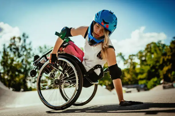 Wheelchair woman performing stunts in skate park - courage and confidence in adaptive sports and hobbies