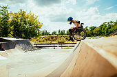 Disabled millennial woman in wheelchair rolls down the hills in skate park