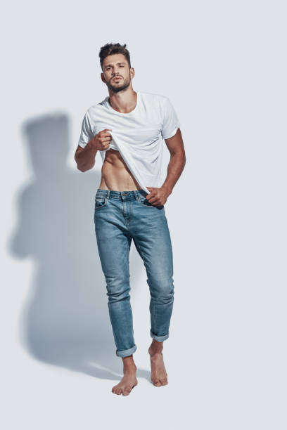 istock Full length of handsome young man looking at camera and undressing while standing against grey background 1167961985